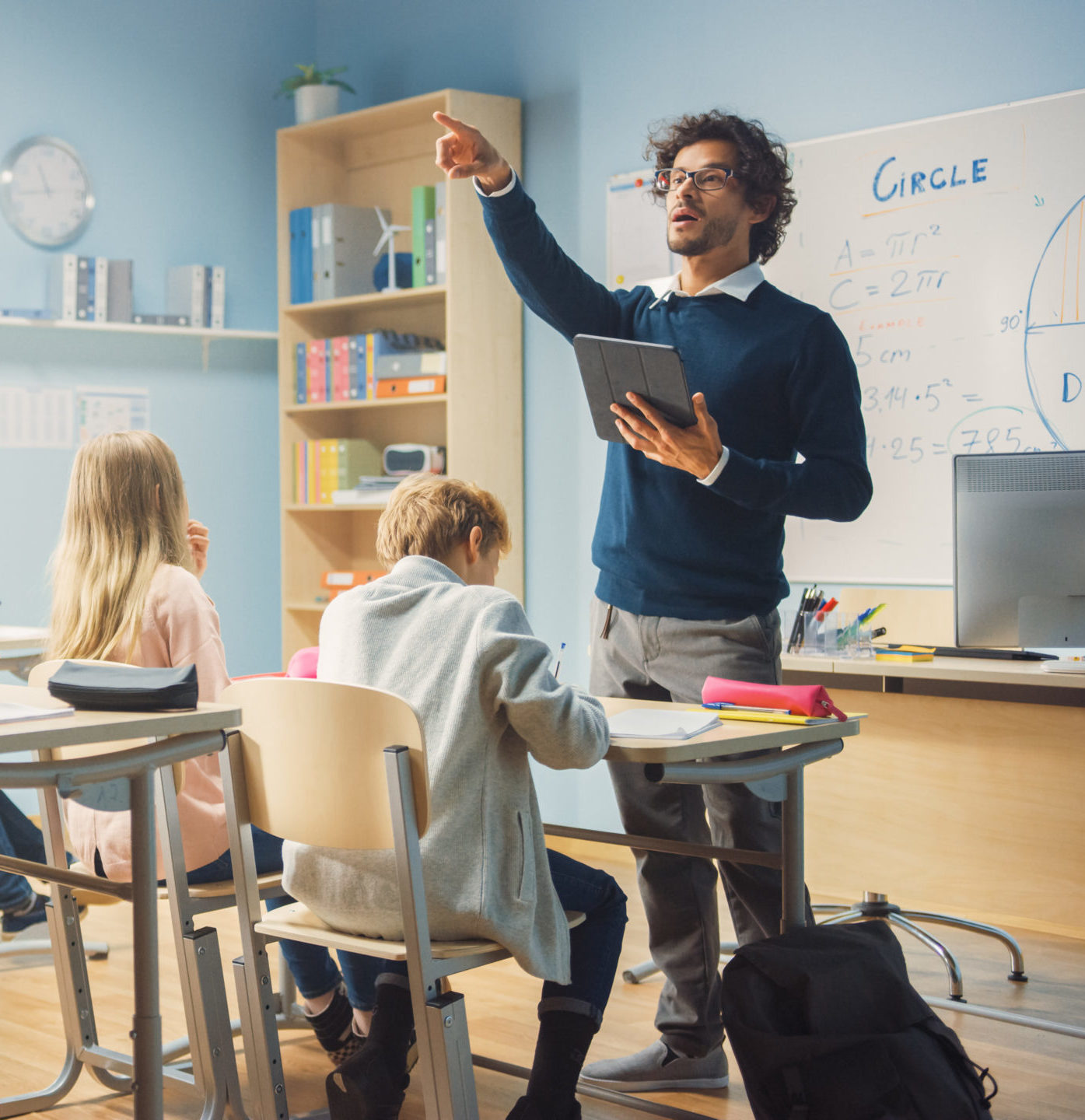 Enthusiastic Teacher Giving a Lesson in Elementary School to Cla